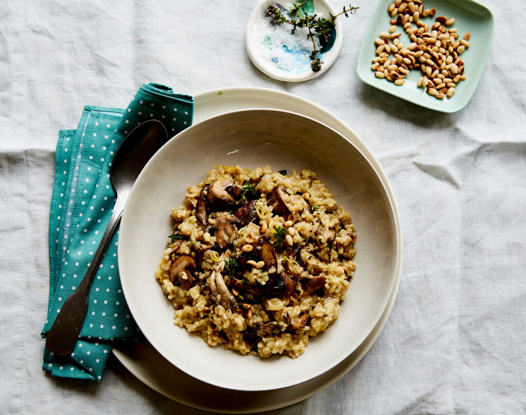 Overhead image of a brown rice risotto, with mushroom and pine nuts.