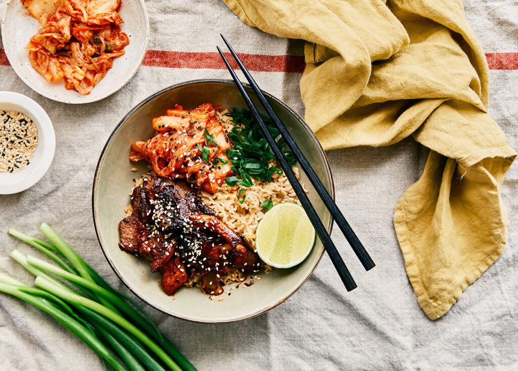 Overhead shot of a bowl of Korean-style BBQ chicken on a bed of rice. 