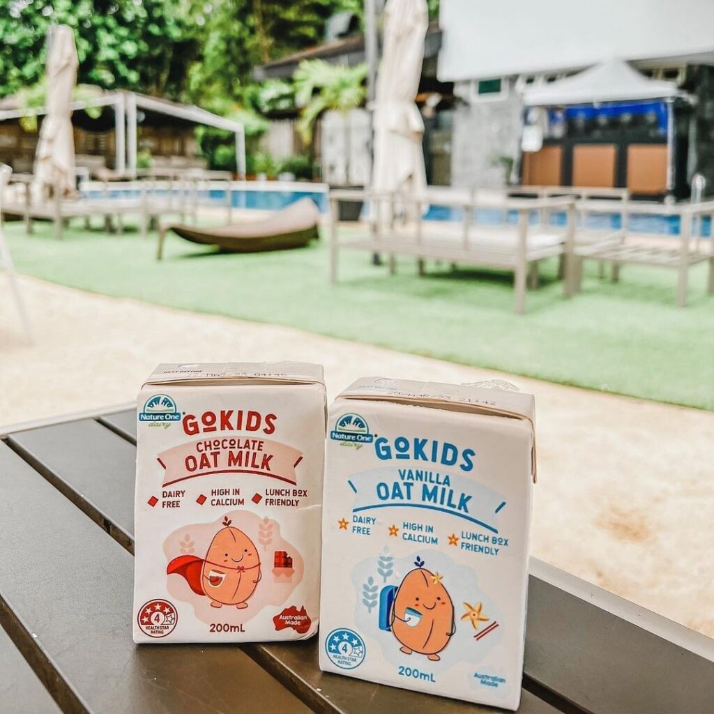 Two single serve cartons of GoKids flavoured oat milks sit on an outdoor table.