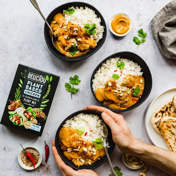 Image from above of three bowls of butter chicken and rice, with a box of Deliciou plant-based chicken lying to the left.