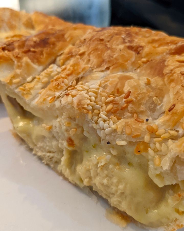 A close up image of a pie cut in half, oozing creamy cheese.