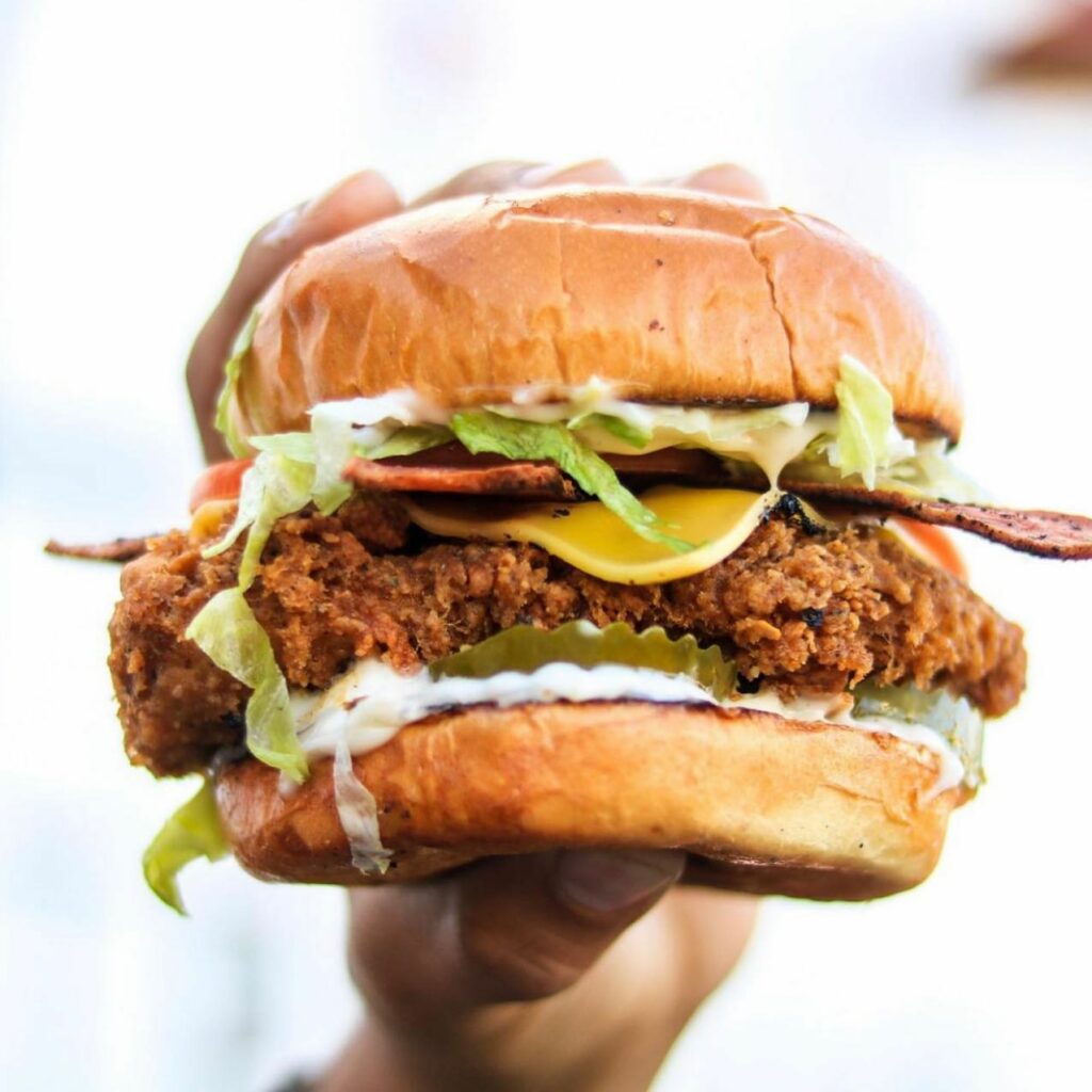 A close up of a chicken burger being held up to camera.