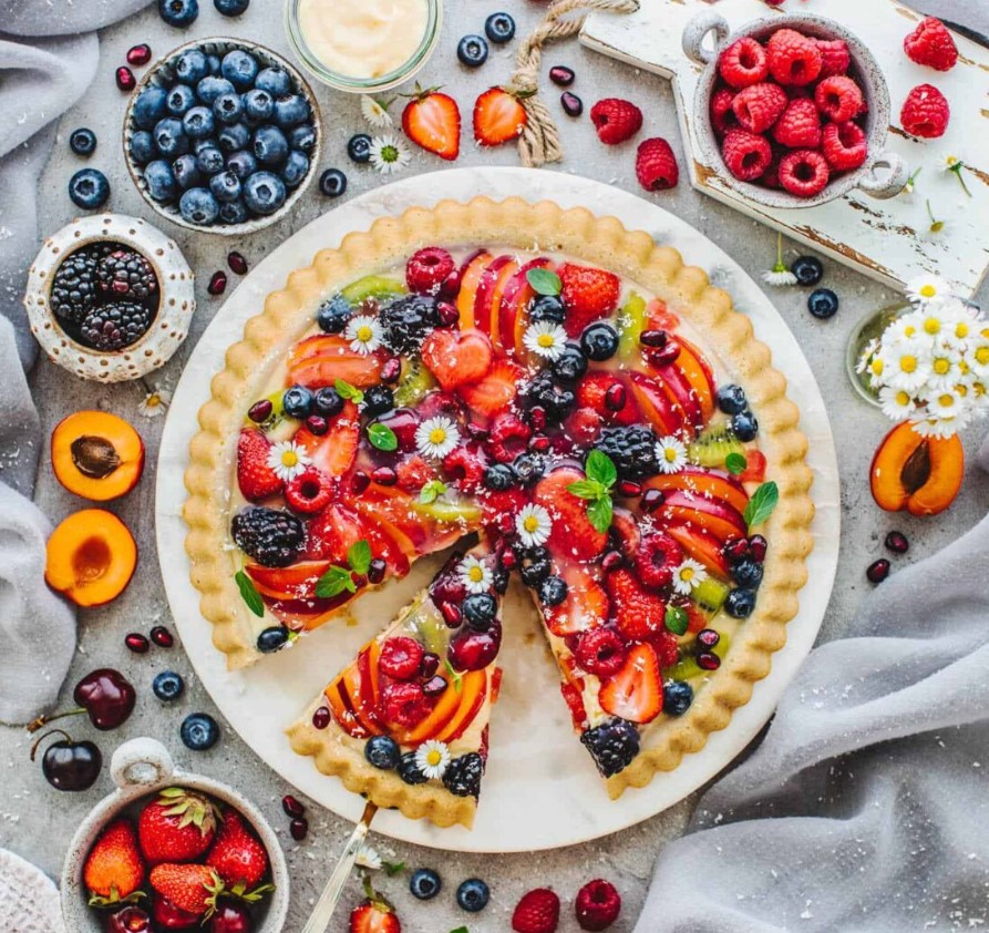 An overhead image of a tart topped with brightly coloured fruit.