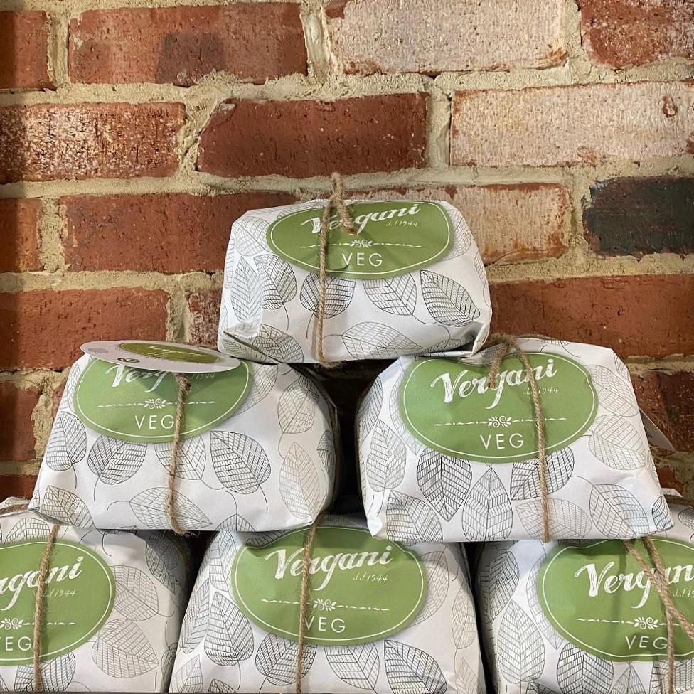 A stack of wrapped panettone against an exposed brick wall.