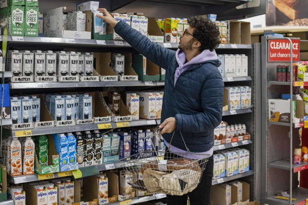 Man shopping in a supermarket selecting a plant milk.