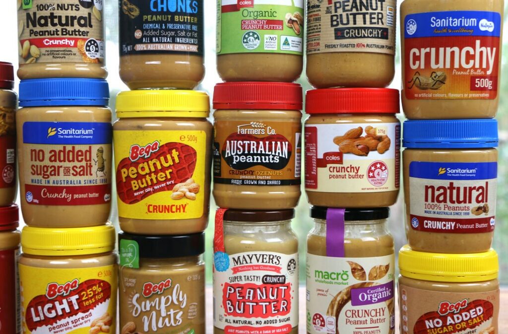 Jars of peanut butter of varying brands, sitting atop each other.