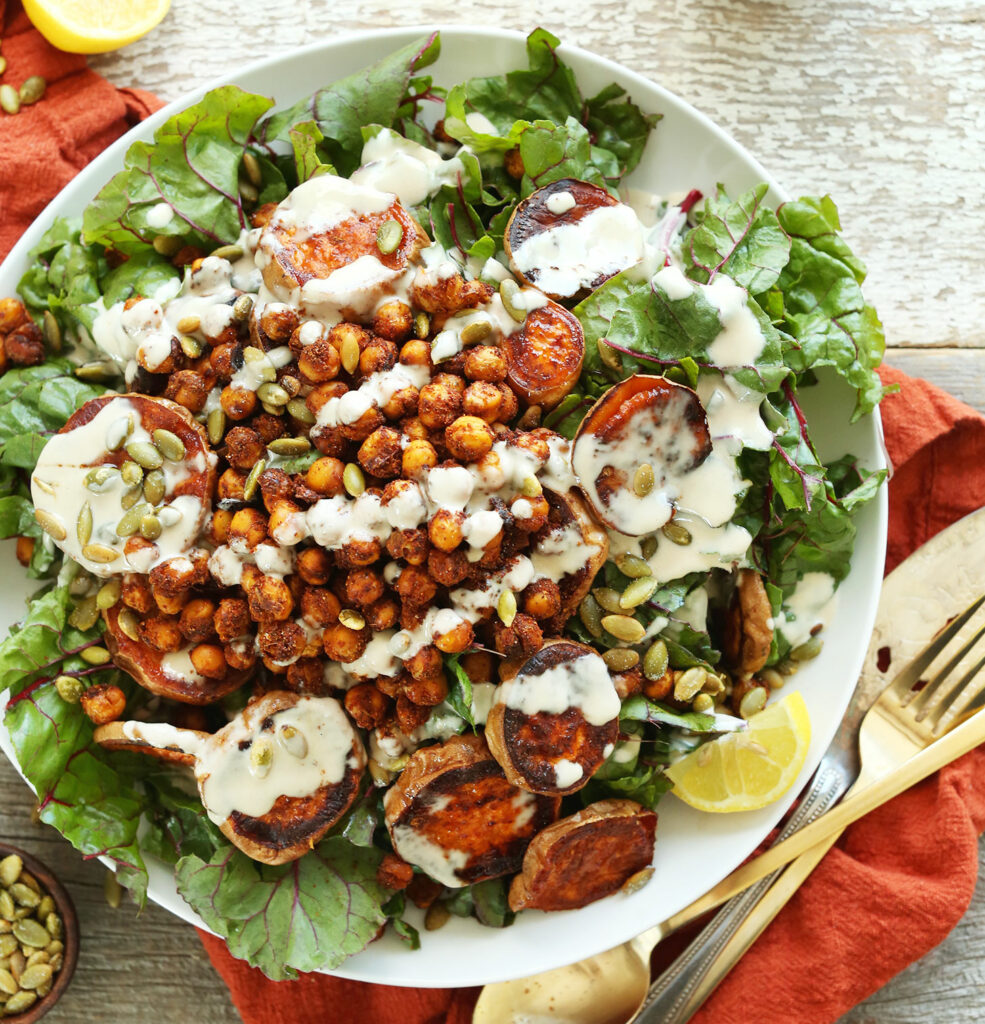 A creamy-looking salad of chickpeas and roasted sweet potato slices on a bed of lettuce.