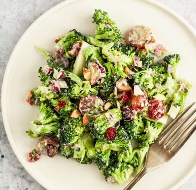 An overhead image of a creamy broccoli salad on a plate with a fork.