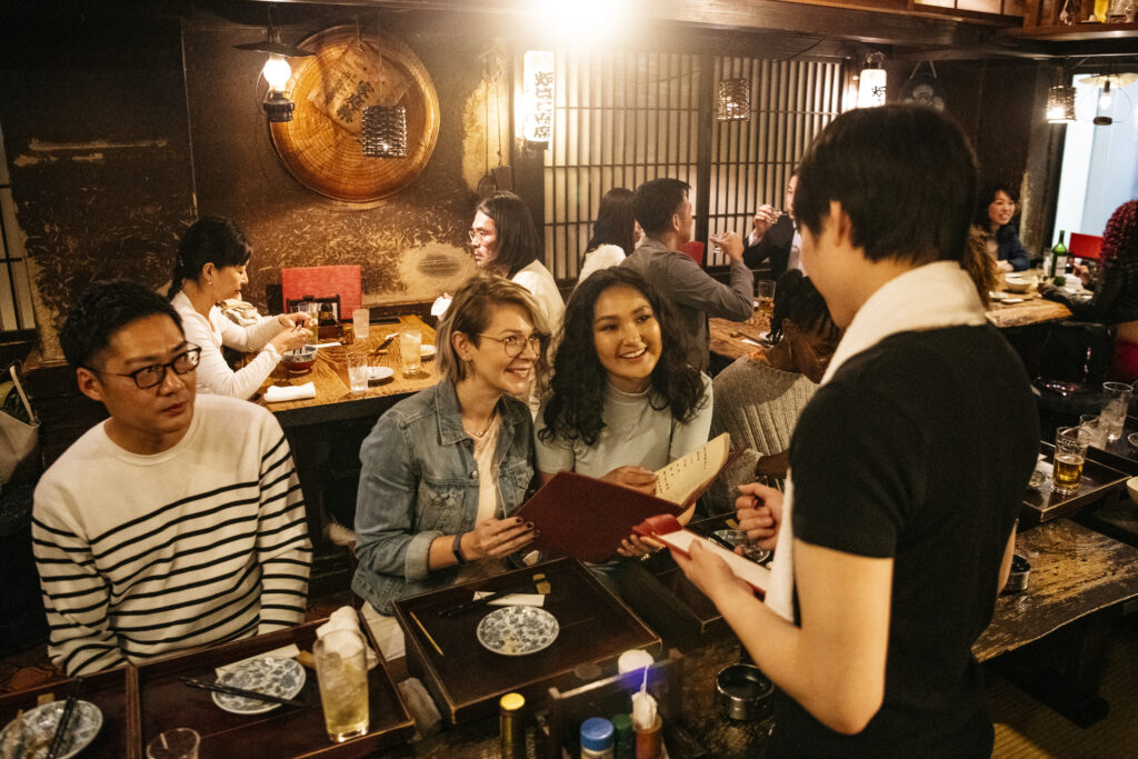 Young women ordering food in busy Japanese restaurant.