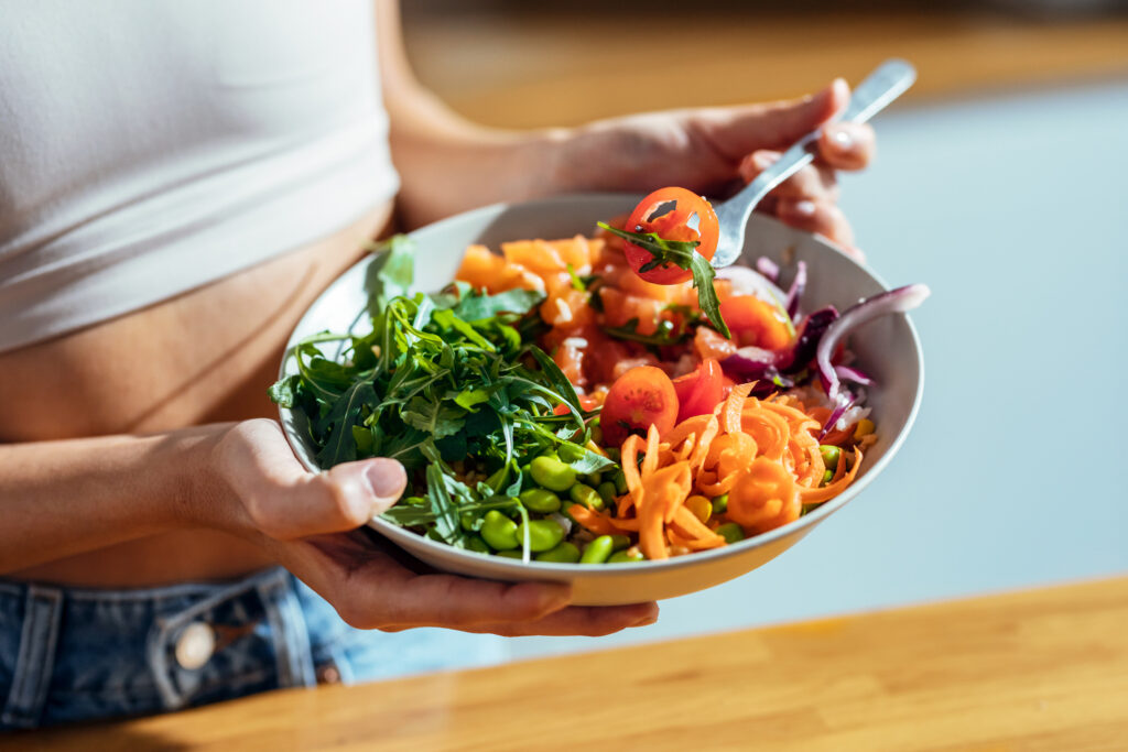 Close up image of a woman eating a healthy plant-based meal in her kitchen.