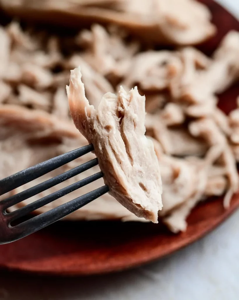 A close up of chunky plant-based roast 'chicken' is being held to camera on a fork.