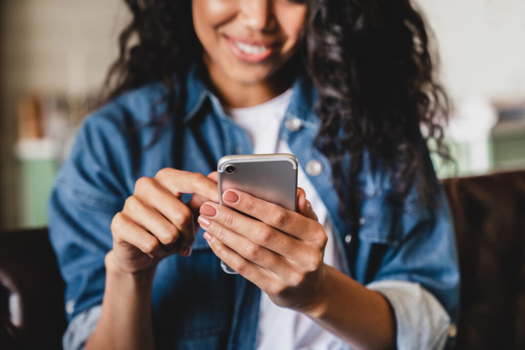 A woman holds her phone in front of her, scrolling social media.