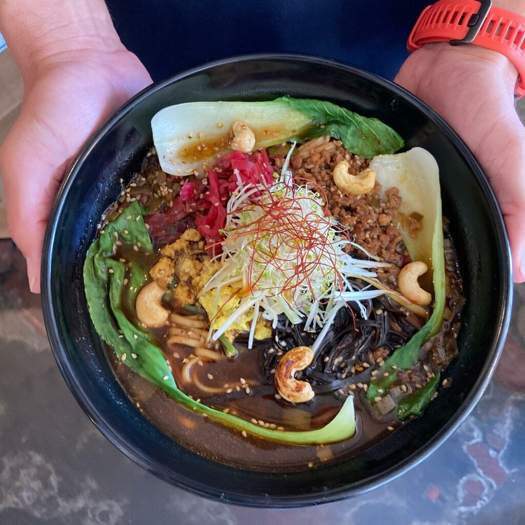 Overhead shot of hands holding a bowl of spicy tofu ramen.