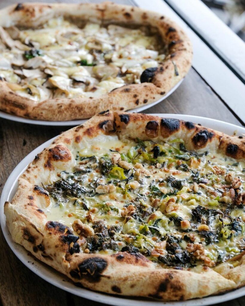 Two different varieties of pizza are shown on a table.