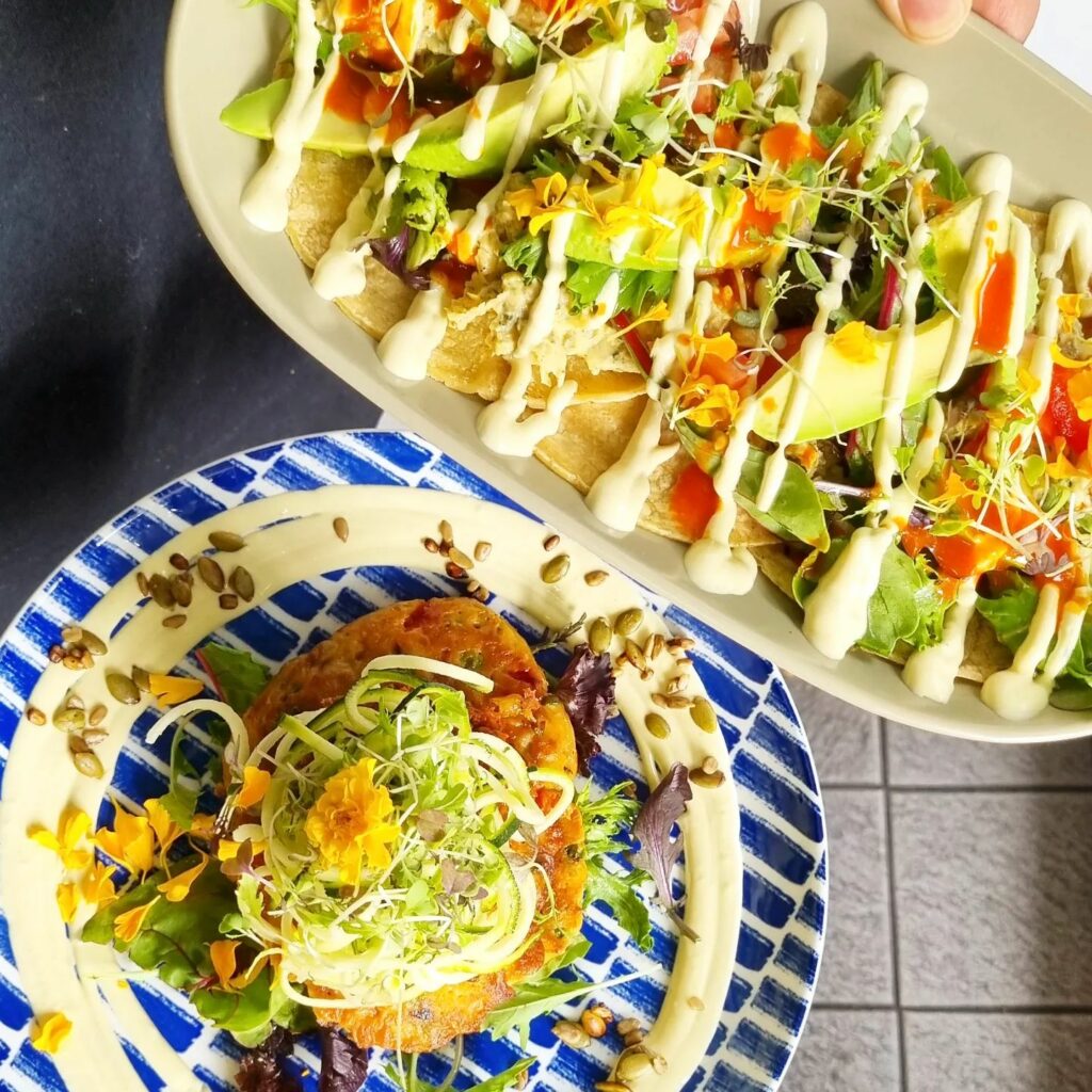 An overhead image of two brunch dishes – fritters and pancakes with colourful toppings.