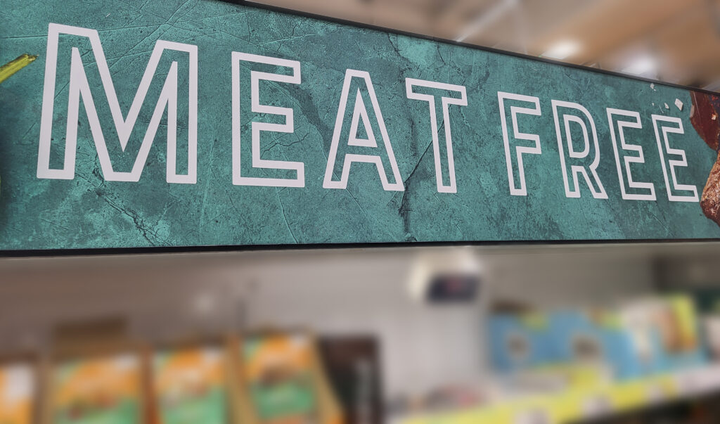 Big overhead sign in supermarket reading 'Meat Free'. 