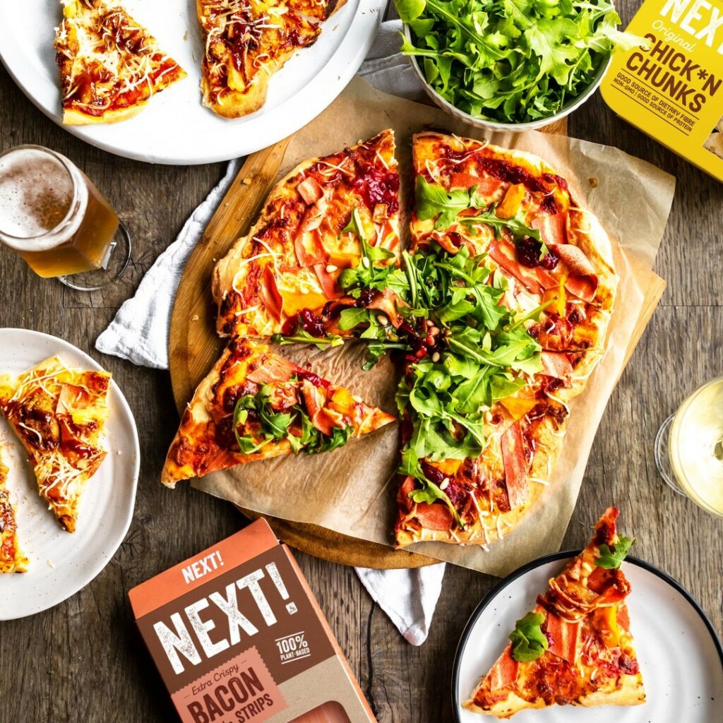 Overhead image of a pizza topped with plant-based bacon. 