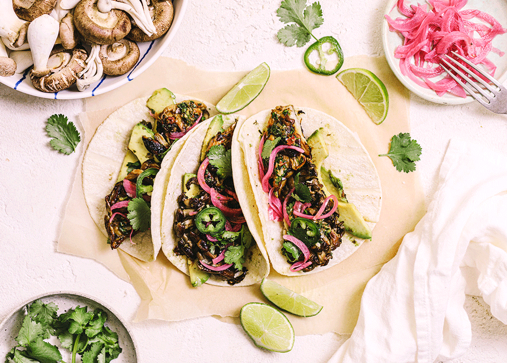 Overhead image of soft tacos filled with mushroom, pickled red onion, and chimichurri. The image is very colourful with green and pink ingredients.