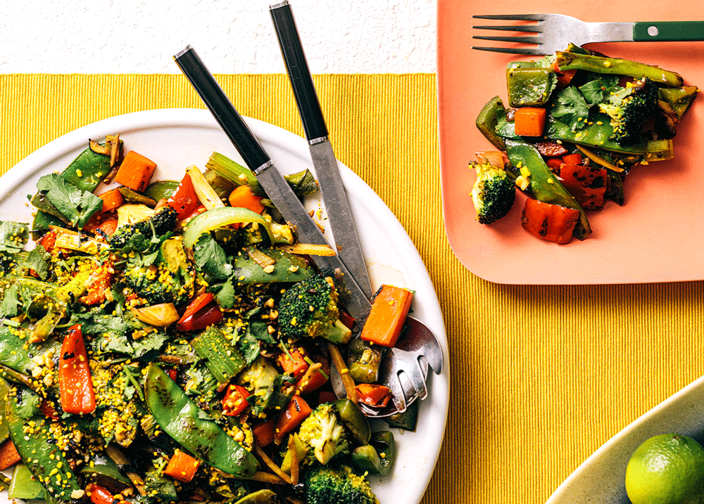 A colourful plate of stirfry on a yellow table runner. 