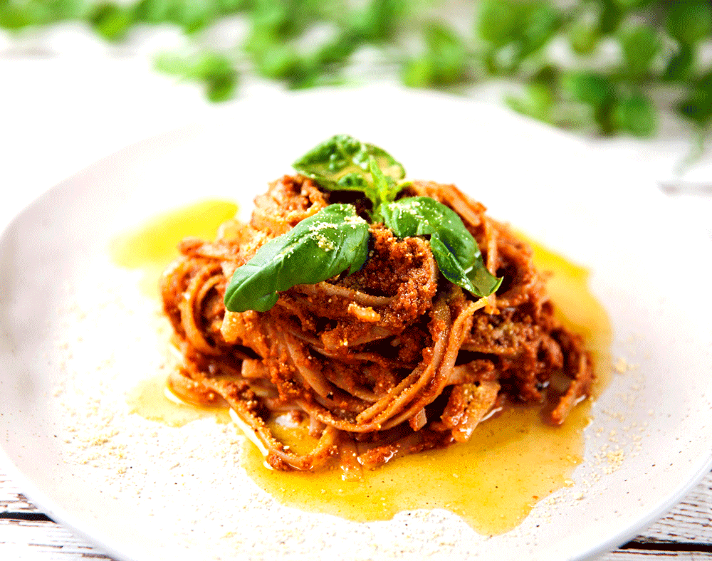 A beautifully presented spaghetti dish, covered in a rich walnut ragu and topped with vegan parmesan.