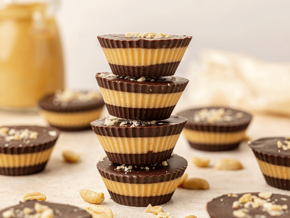 Home made peanut butter cups sit on a bench, stacked upon each other.