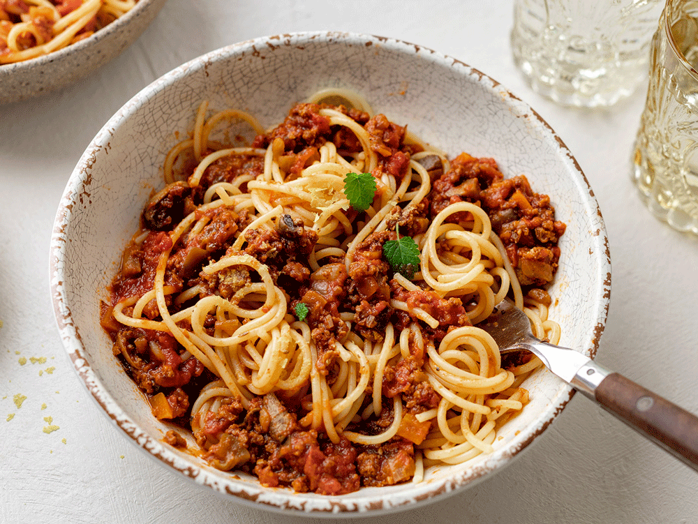 A fork sits in a bowl of spaghetti bolognese made with TVP.