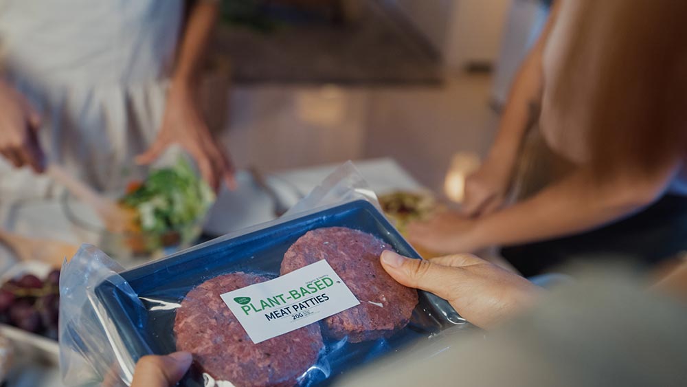 An over-the-shoulder view of a person holding a packet of two plant-based meat patties.