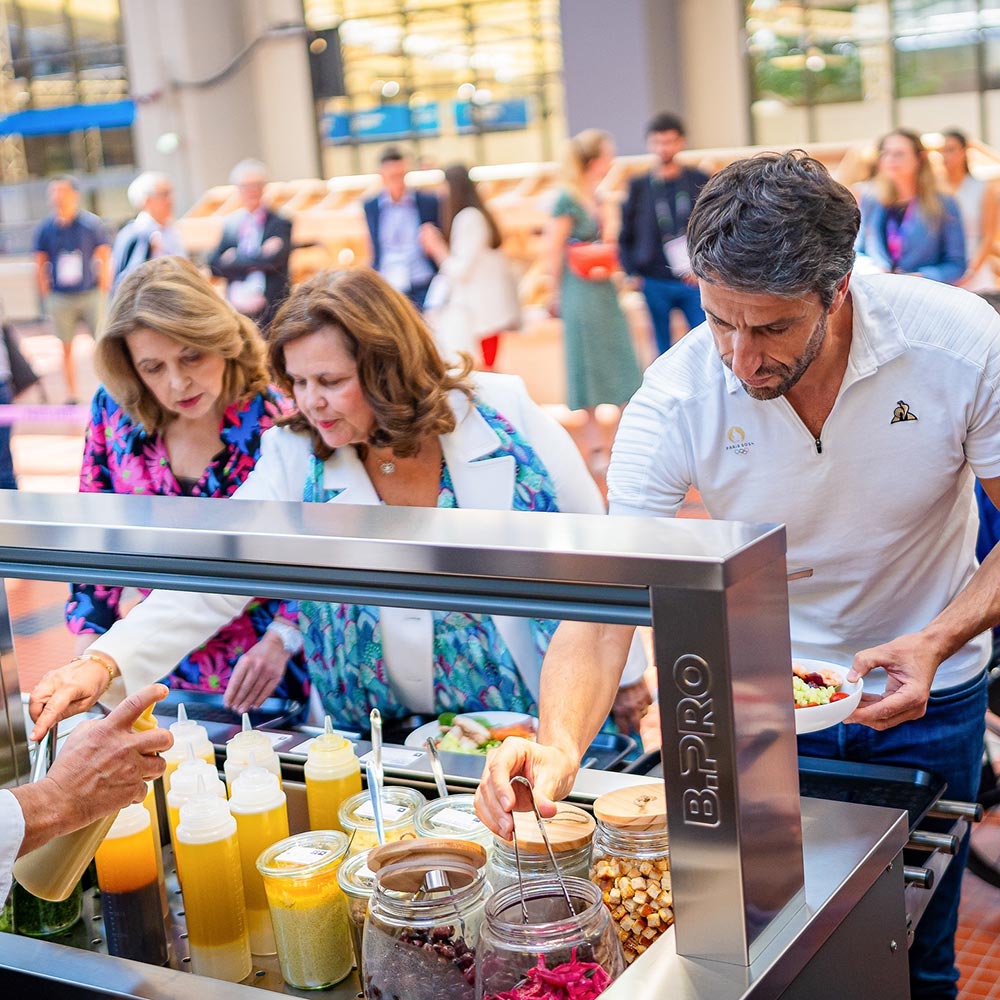 Members of the Olympic Committee at the self-serve food station in the Olympic Village restaurant. They are plating up with a variety of foods.