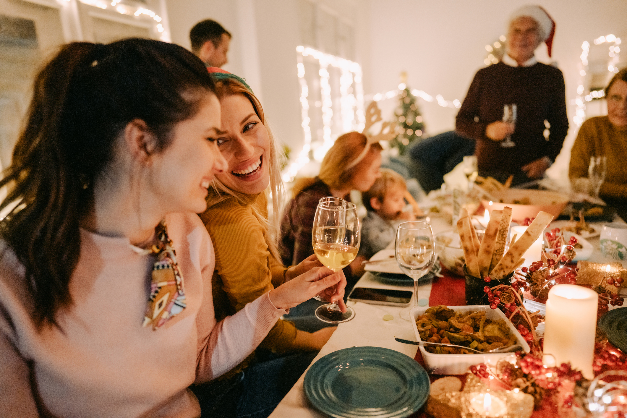 Happy friends sitting around christmas lunch dinner table