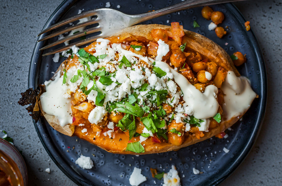 Delicious looking baked sweet potato with cheese and herbs on top