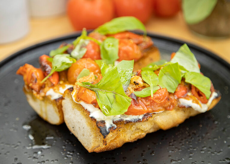 Charred tomatoes on a toast with herbs on top