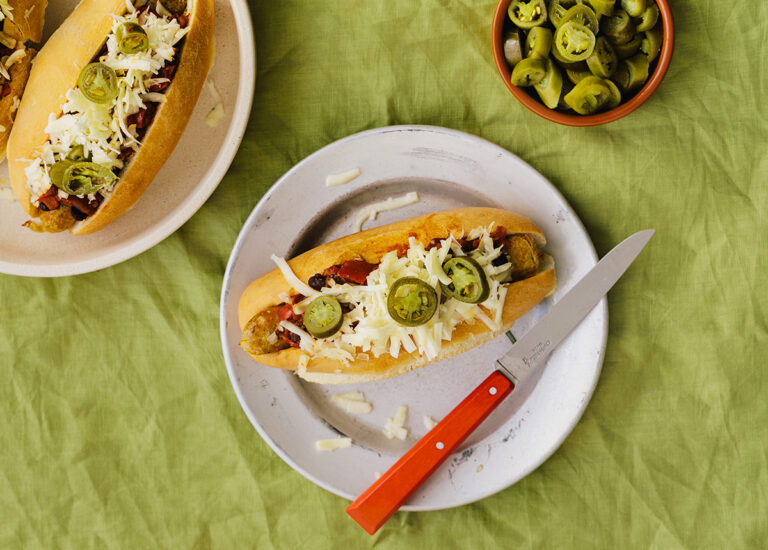 A delicious vegan chilli hot dog in a plate with knife