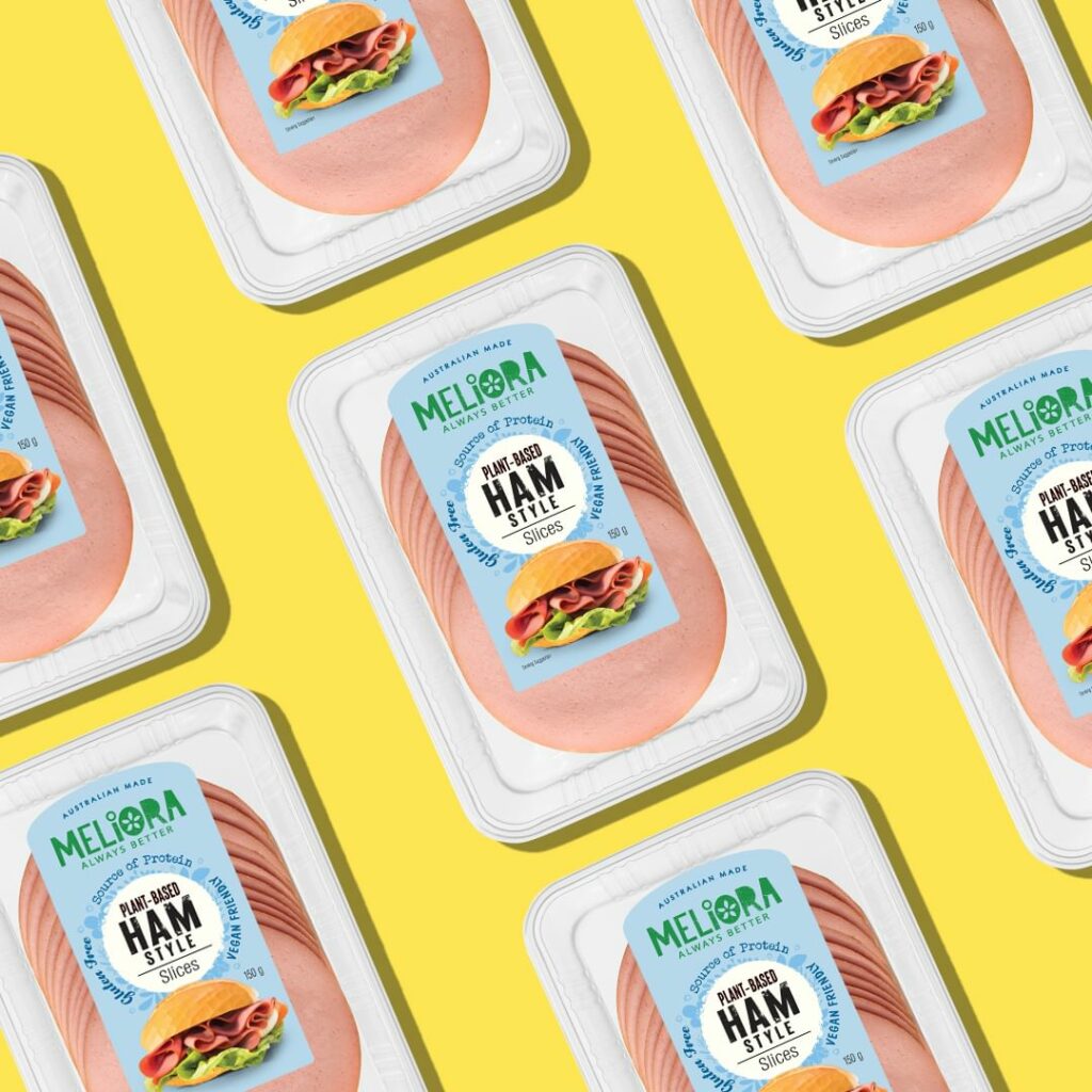 Packets of Meliora plant-based ham are laid out in a diagonal pattern on a yellow background.