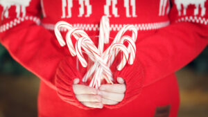 Close up image of a childs hands holding candy canes.