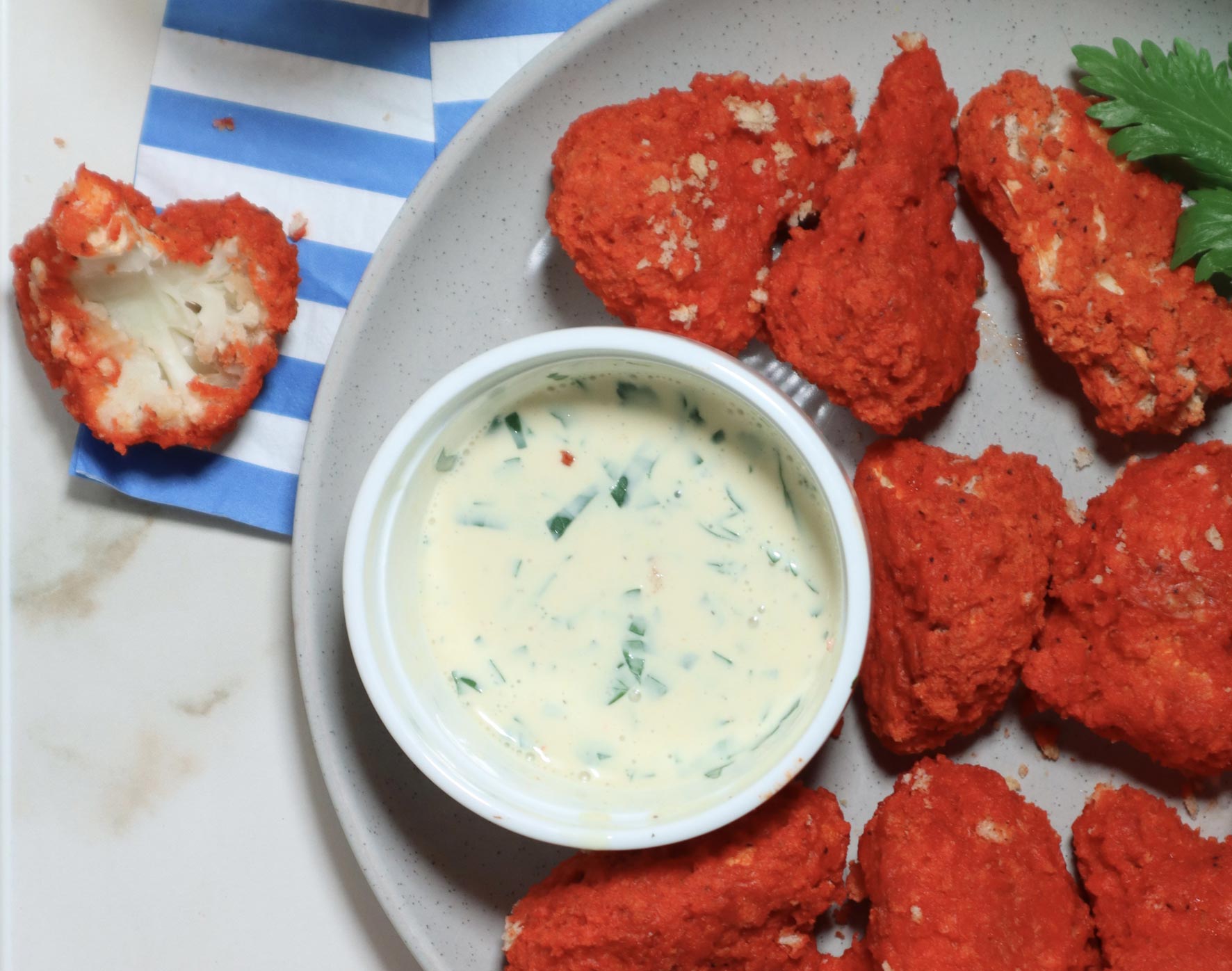 Overhead image of deep-fried buffalo cauiflower bites with a side of ranch.