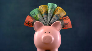 Pink Piggy bank on dark blue background, stuffed with Australian cash.