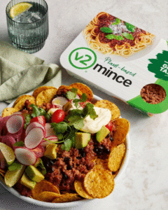 A tray of nachos covered in a delicious looking plant-based "beef" mince form V2. A V2 pack sits to the side.