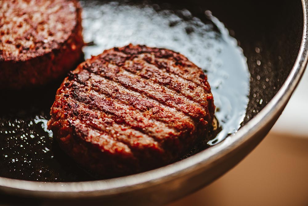 Close-up of plant-based meat patties in a frypan.